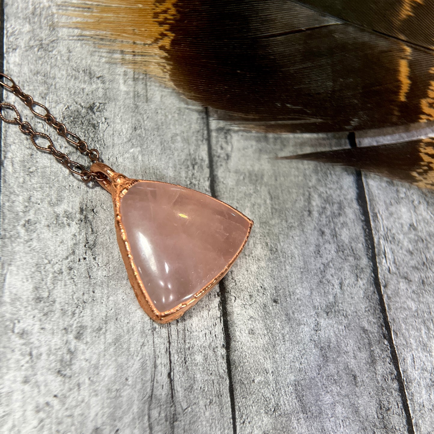 smooth rose quartz crystal pendant on matching copper chain necklace.