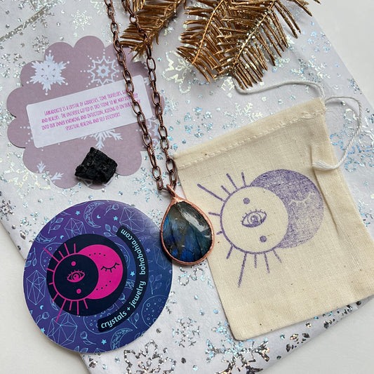 Packaging for healing crystals and handmade jewelry includes a gift bag, metaphysical crystal card, and black tourmaline.